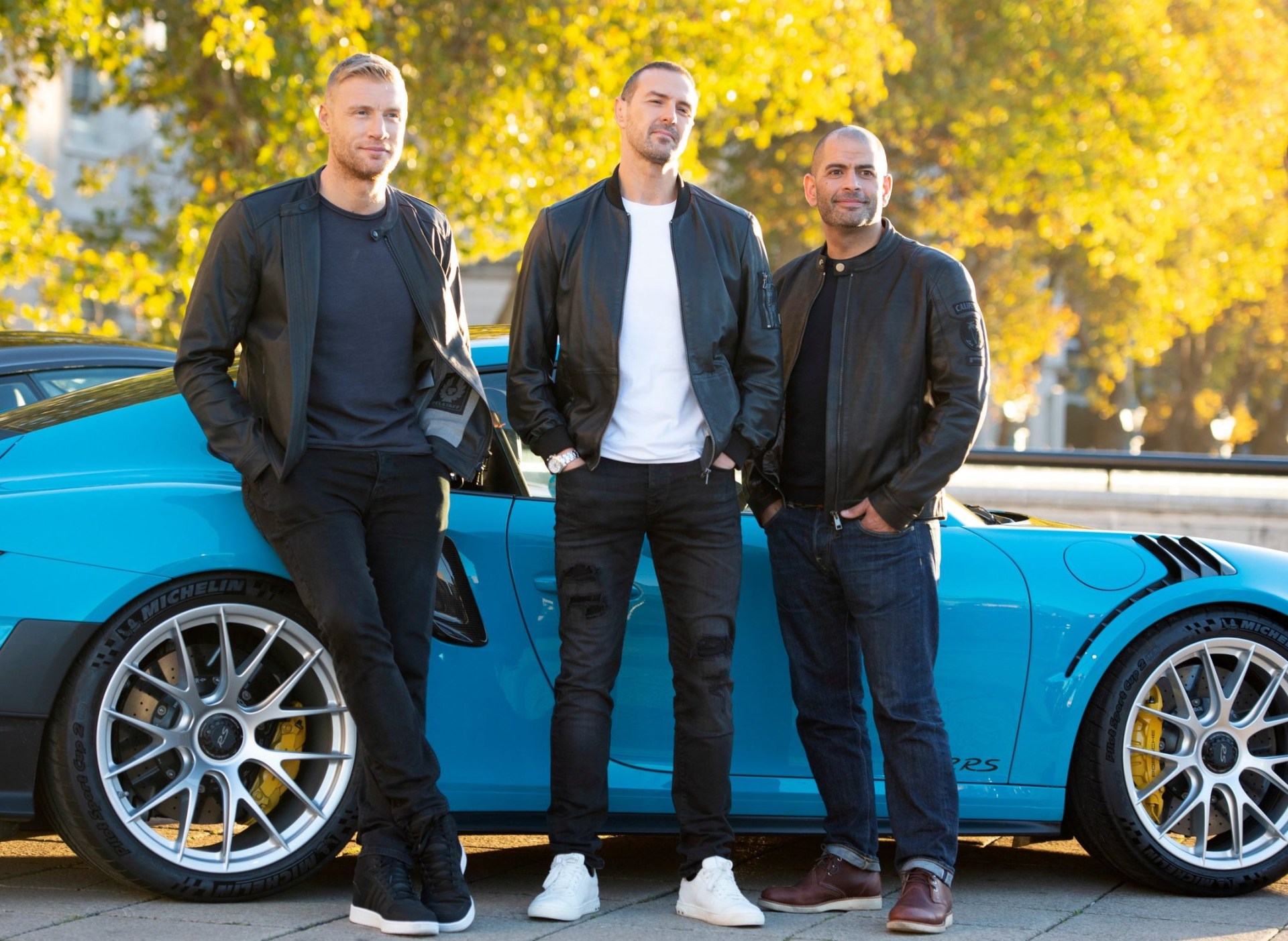 Paddy McGuinness, Andrew 'Freddie' Flintoff and Chris Harris on the embankment of the the River Thames in central London, posing in front of a blue car.