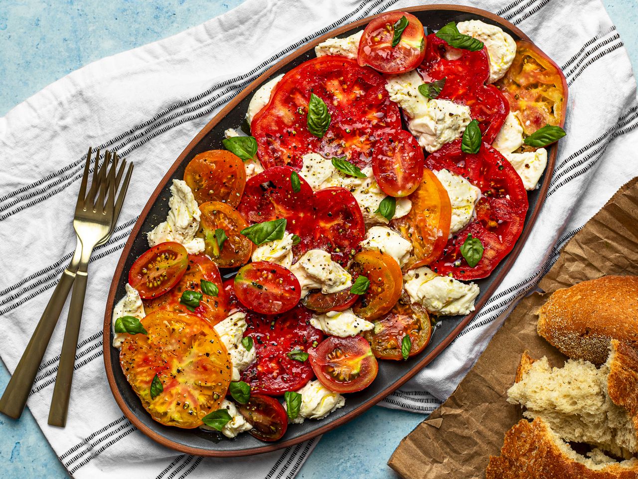 An oval ceramic platter holding caprese salad.