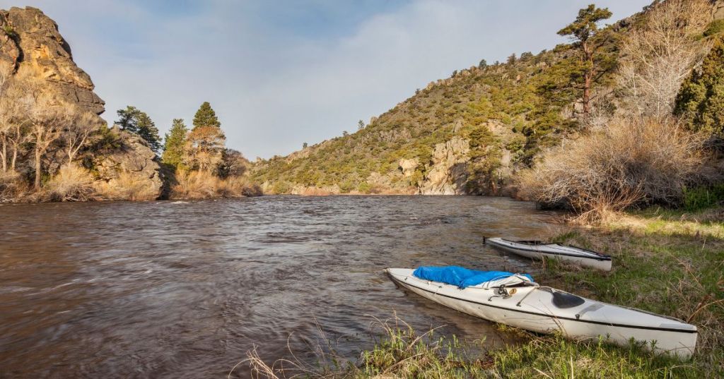 Views of the scenic North Platte River near Casper in Wyoming, with two kayaks on the banks, surrounded by a rugged terrain.