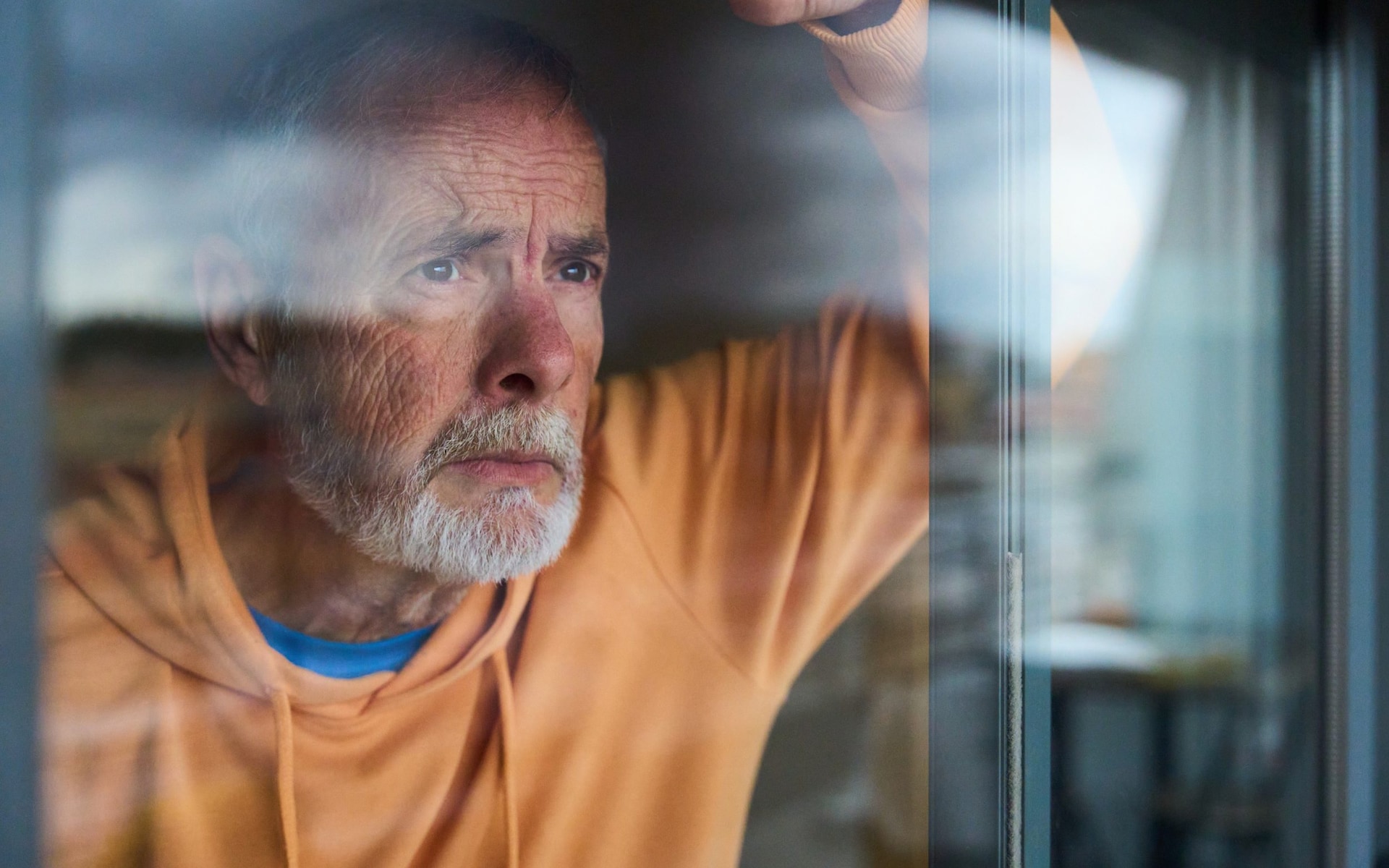 Mature man looking through window with worried expression