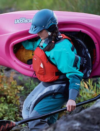 model carrying a kayak wearing a red side entry pfd