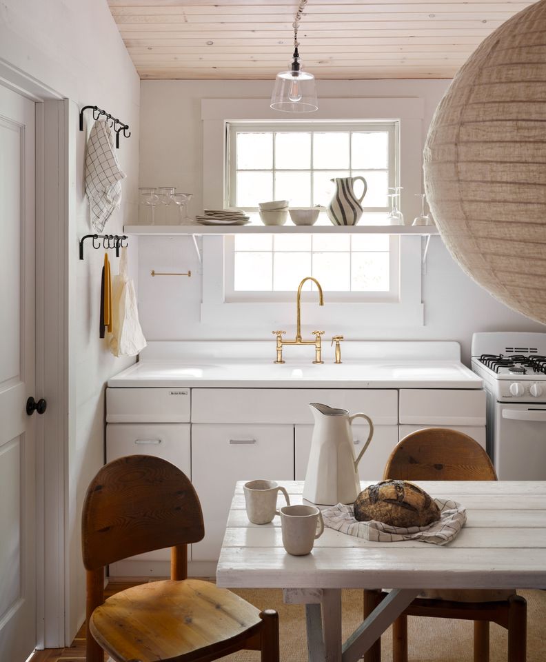 Cozy kitchen scene with a table chairs a window and various kitchen items arranged on shelves and the tabletop
