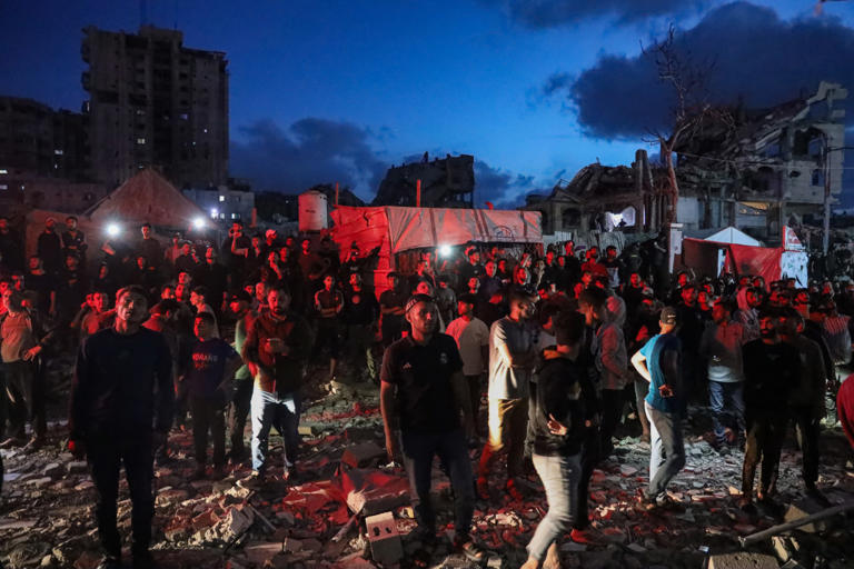Residents watched a building burn Friday after it was struck in Al-Rimal, a neighborhood in Gaza City.