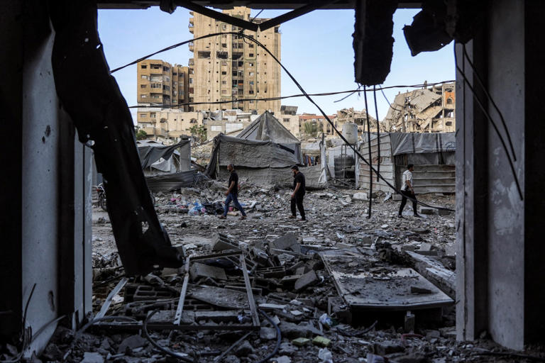 People in Al-Rimal walked over rubble on Saturday outside a residential building hit the previous night.