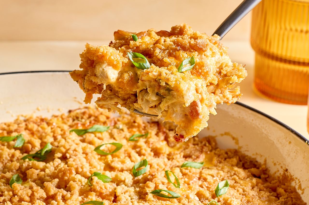 Spoonful of chicken casserole being served from a dish garnished with green onions
