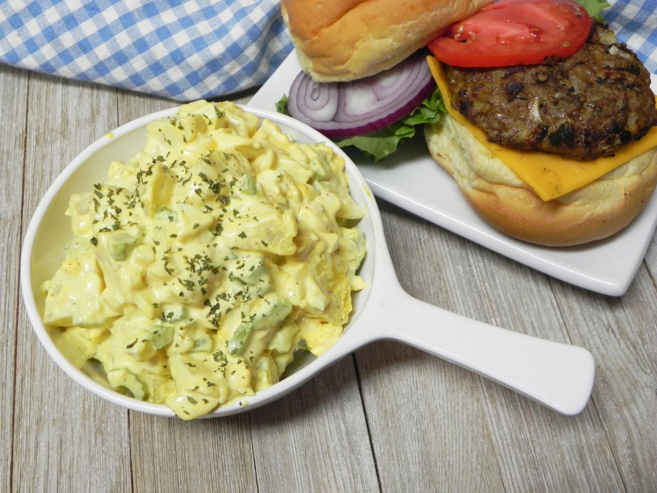 creamy potato salad in white bowl sprinkled with dried herbs