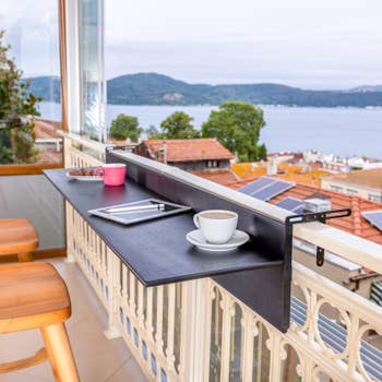 Foldable balcony table setup with a tablet, coffee cup, and scenic lake view in the background, ideal for outdoor workspaces