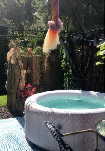 Inflatable whirlpool in a garden setting with hanging decor and plants around. A serene, private backyard oasis