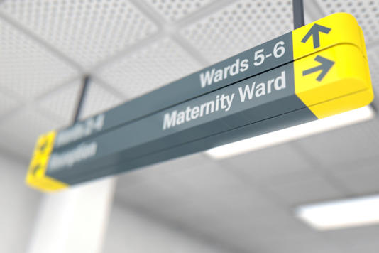 A ceiling mounted hospital directional sign highlighting the way towards the maternity ward