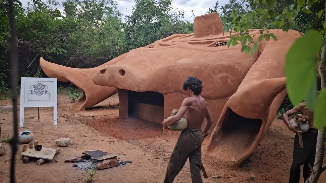 Builders shape a buffalo-shaped mud house by hand