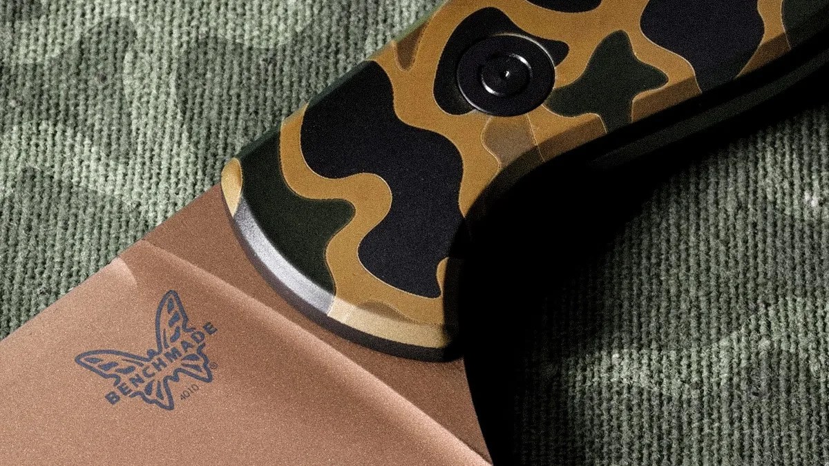 Close-up of a Benchmade knife blade with a butterfly logo and a camo-patterned handle.