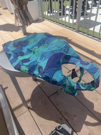Reusable shopping bag with a swirly pattern, placed on a patio chair, suggesting eco-friendly shopping choices