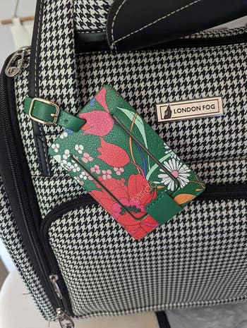 Houndstooth bag with a floral luggage tag featuring red and pink flowers. The bag has a