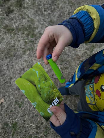 Child holding a green tube and a card with a snake image labeled