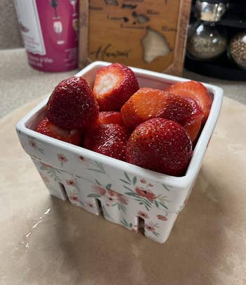 Fresh strawberries in a decorative floral ceramic basket on a kitchen counter