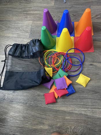 Children’s play set with colorful cones, rings, and bean bags next to a mesh drawstring bag, displayed on a wooden floor