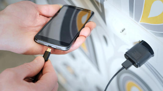 Close-up image of a man connecting a phone to a charger