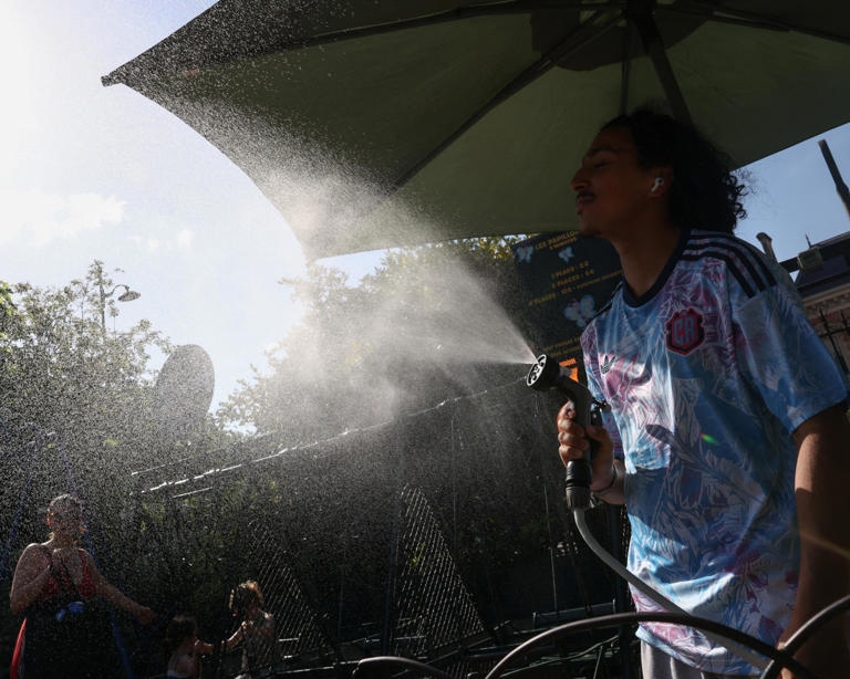 A man spraying mist on people in Buttes Chaumont park in Paris. Photograph: Tom Nicholson/Reuters