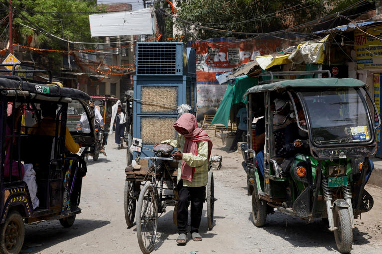 A man with his head covered with a cloth transports a cooler on a cycle cart along a street, on a hot summer day (AFP/Getty)