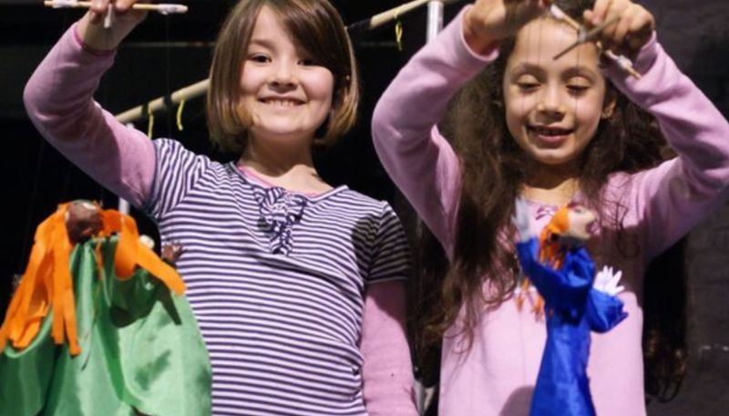 Two girls holding up homemade puppets