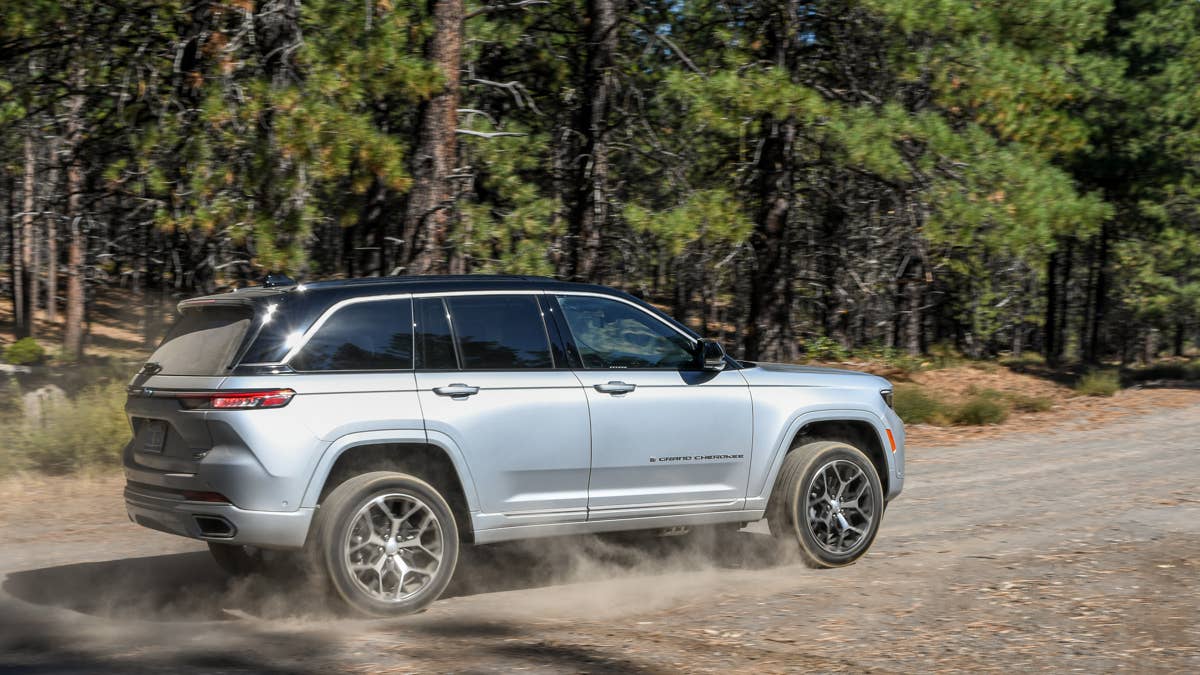 2025-jeep-grand-cherokee-4xe-summit-reserve-silver-rear-angled-view-off-road-dirt-driving