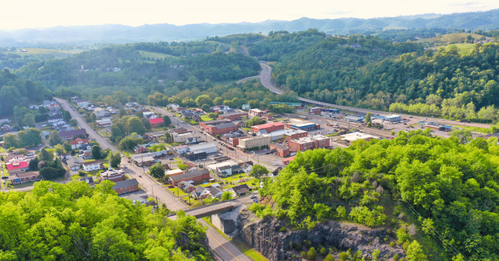 Aerial view of Abingdon, Virginia, showing historic brick buildings, streets, and lots of green trees with mountains in distance.