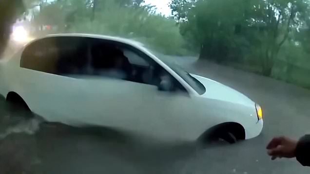 Police officer enters flooded road to rescue baby from stranded car