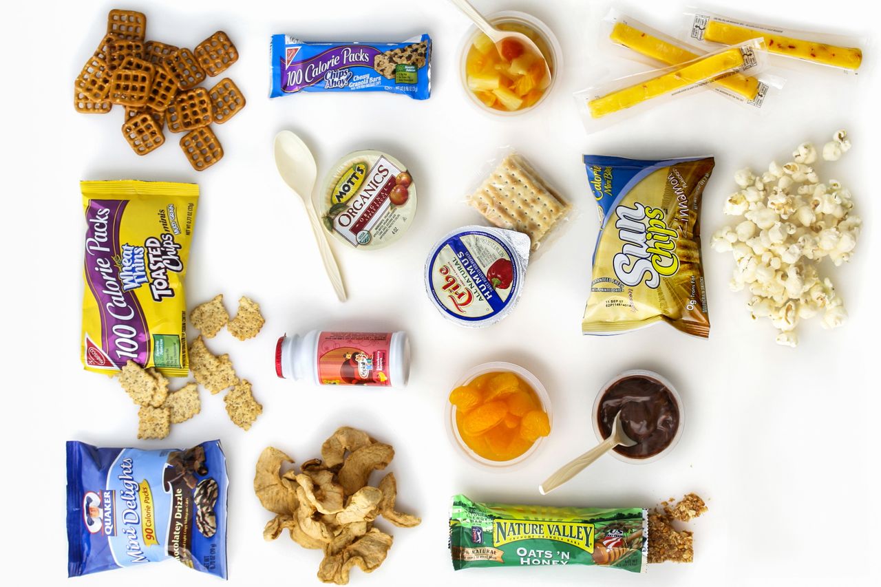 Various packaged snacks crackers and beverages arranged on a white surface
