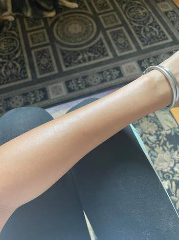 Reviewer with sunscreen sprayed on arm showing lightweight and sheer formula