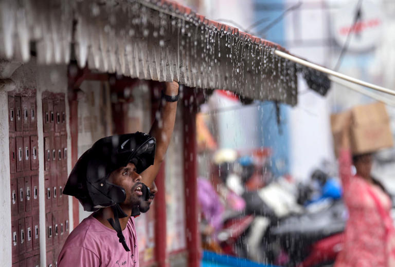 A man stands under a shed amid rainfall. (Photo: PTI)
