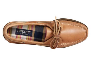 Top view of a tan Sperry boat shoe with a bow, featuring a plaid inner lining and visible brand logo