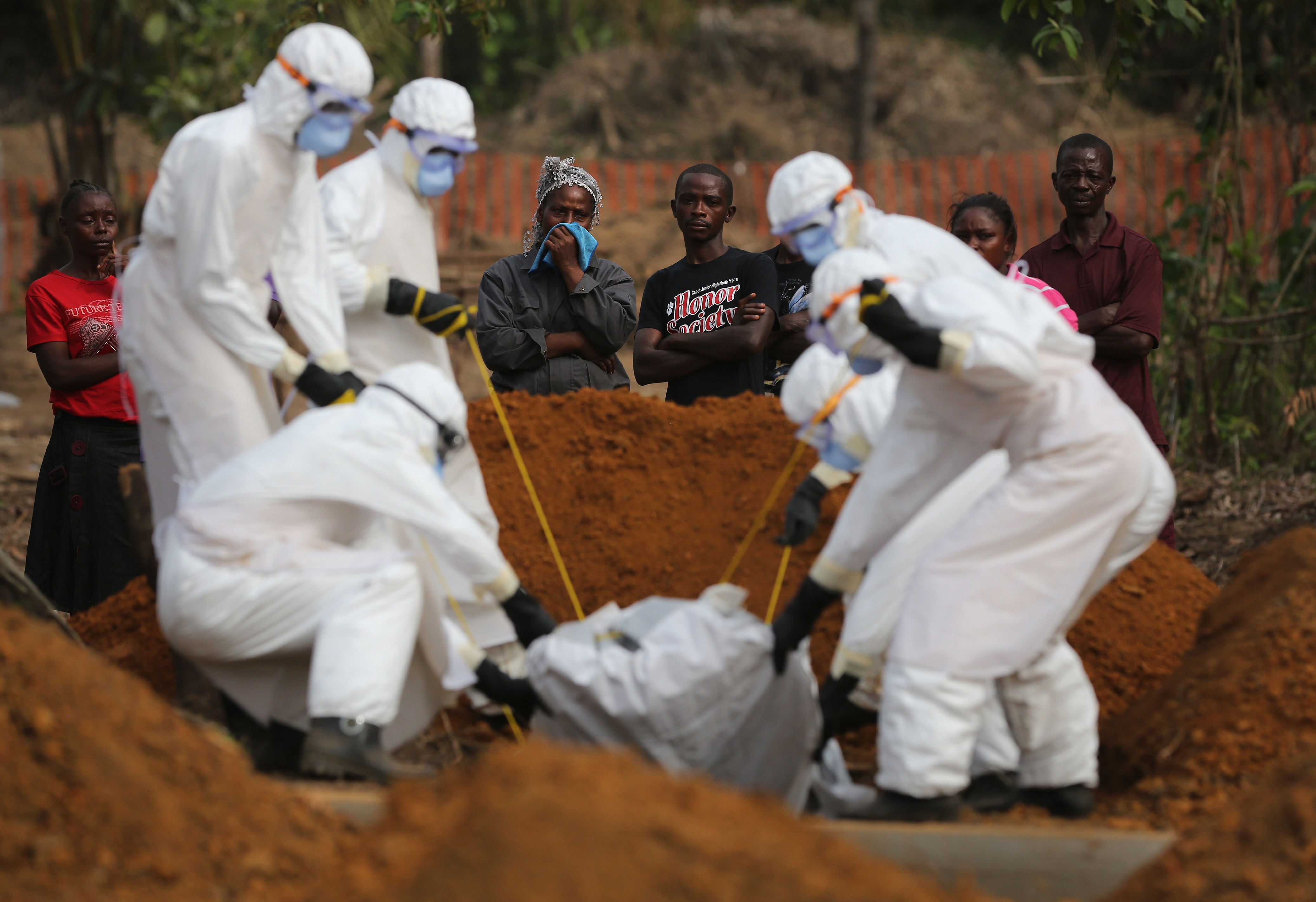 A family watches as a burial team lowers their loved one into a grave at the U.S.-built cemetery in Liberia for ‘safe burials’ in 2015 (Getty)