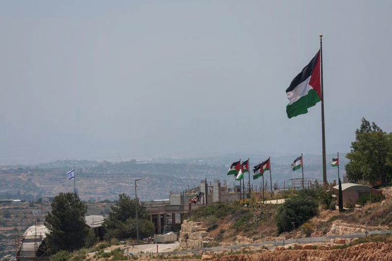 Un drapeau israélien flotte sur une nouvelle colonie israélienne, derrière des drapeaux palestiniens près de Ramallah, en Cisjordanie occupée par Israël. /Photo prise le 1er juin 2026/REUTERS/Mohammed Torokman