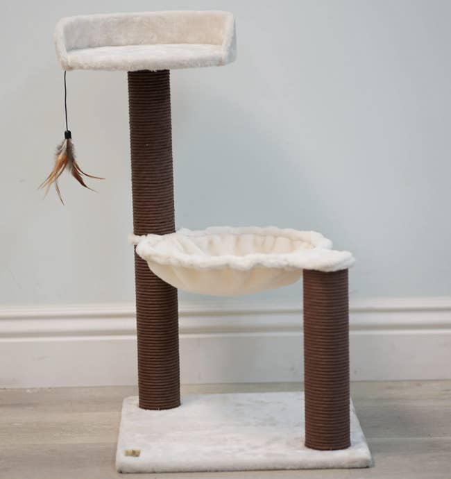Cat tree with two levels: a top perch with a hanging feather toy and a mid-level hammock, supported by two sisal-wrapped posts
