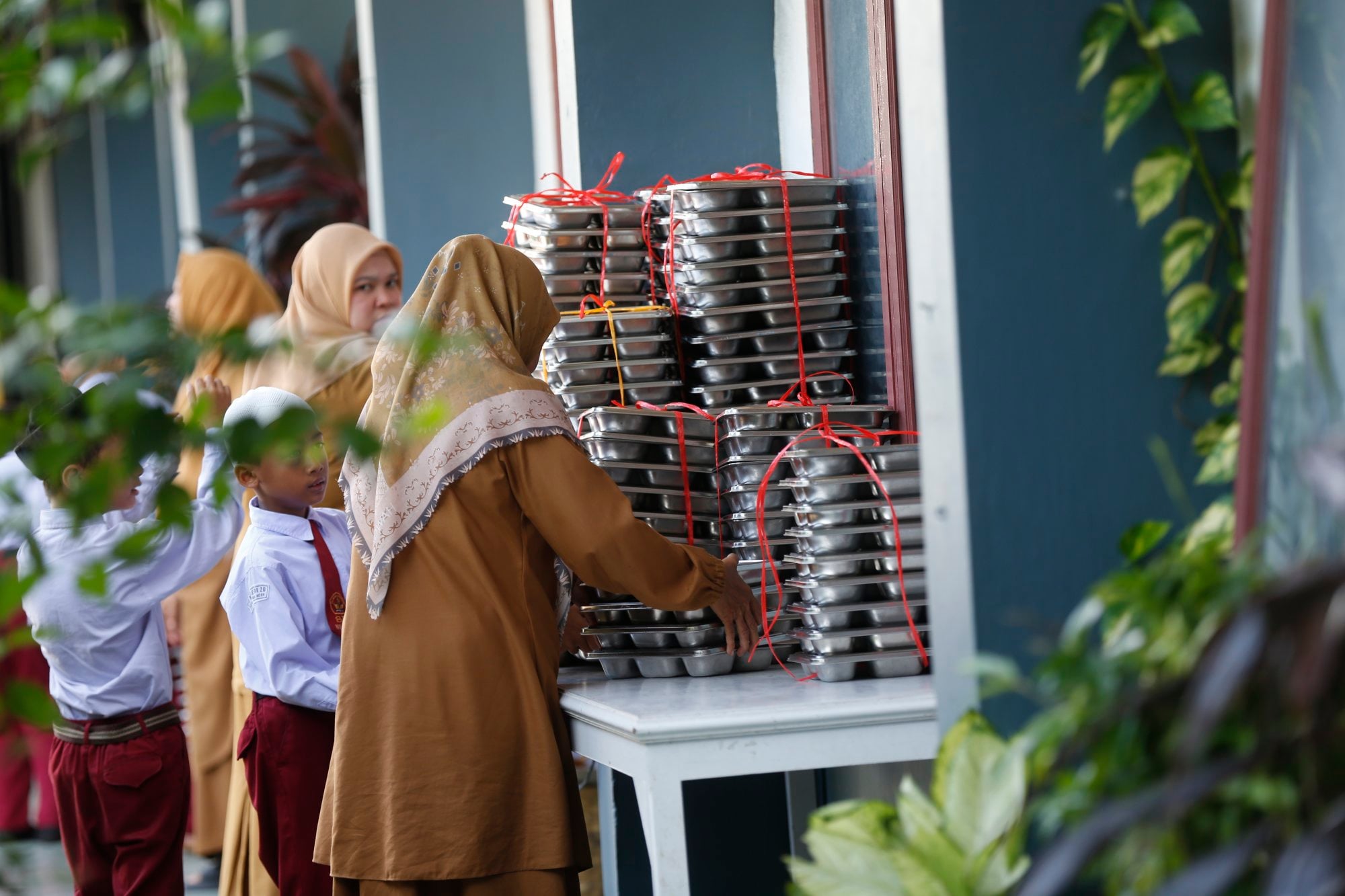 A teacher distributes free meals for students in a school in Banda Aceh, Indonesia last month. Photo: EPA