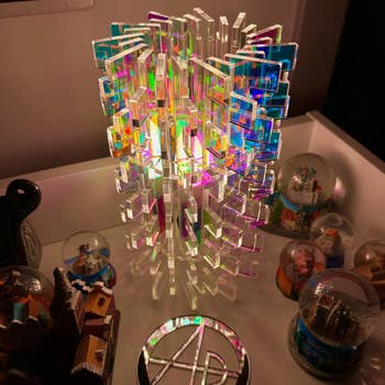 Intricate acrylic sculpture with geometric design, surrounded by various collectible snow globes on a display shelf