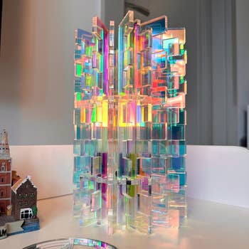 Intricate, reflective acrylic sculpture with geometric patterns; holographic appearance casts colorful light reflections on surrounding surfaces