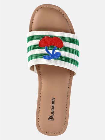 A beaded slide sandal with a green and white strap and cherries decorating it