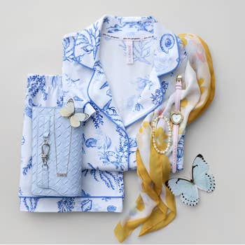 Blue floral pajamas with a silver clutch and butterfly-themed accessories, including a scarf, watch, and bracelet, styled for a shopping feature
