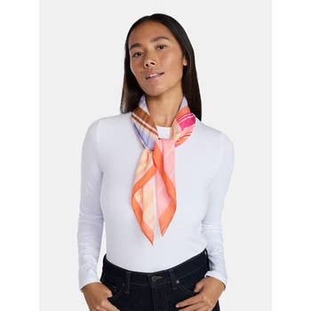 Person wearing a patterned scarf and white long-sleeve top, paired with dark jeans