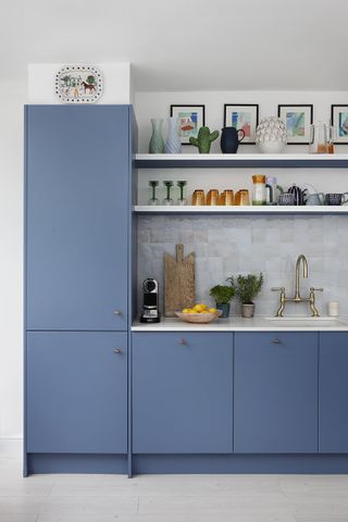 A kitchen with blue cabinets and an iridescent backsplash