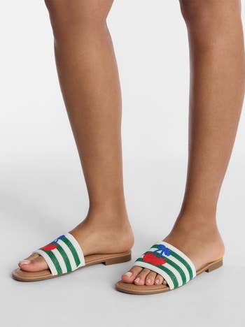 Person wearing striped slide sandals with beaded cherry design