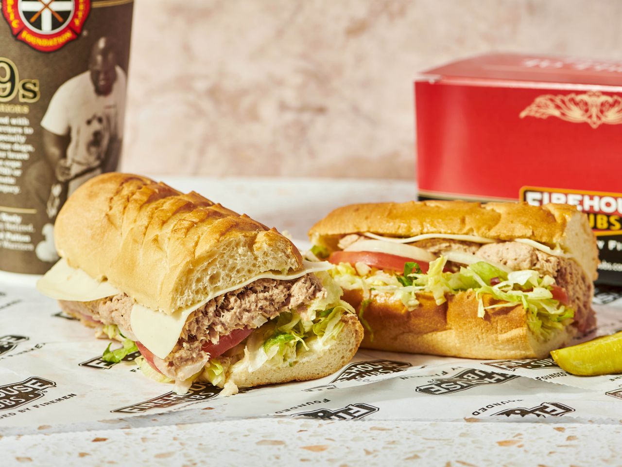 Firehouse Subs tuna sandwiches on white paper with logo, cup, and box.