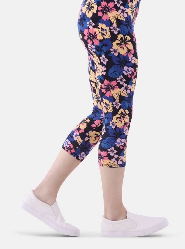 Person wearing floral pattern leggings and white slip-on shoes, side view