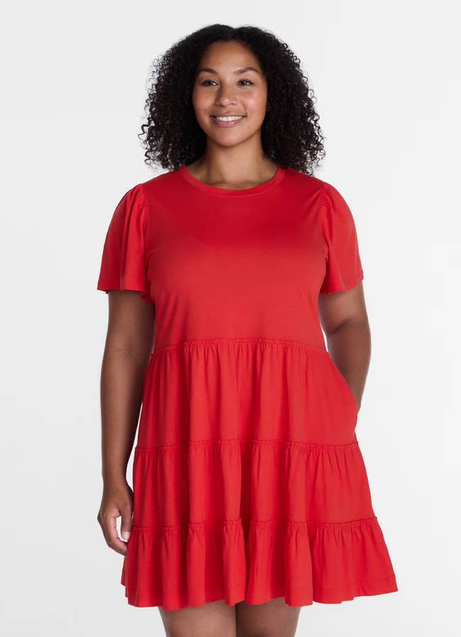Person in a tiered, short-sleeve dress standing and smiling