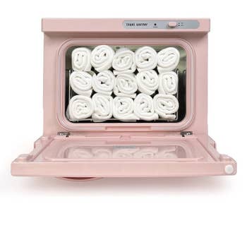Open towel warmer with neatly stacked rolled towels inside