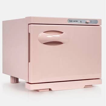 Small, pink towel warmer with a curved handle and digital control panel on the top right side