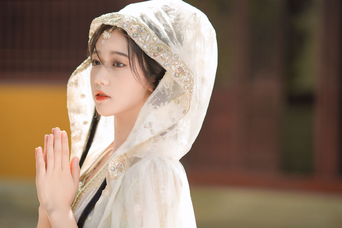 身披素白绣花斗篷汉服，伫立古寺黄墙之下，撑一柄素色油纸伞，在满树金黄银杏与落叶间，静赏古院独有的温婉秋光。