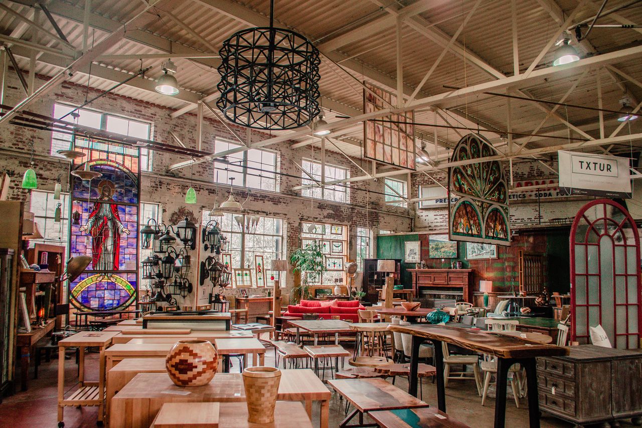 Interior of a store with various furniture and decorative items including stained glass windows and wooden tables