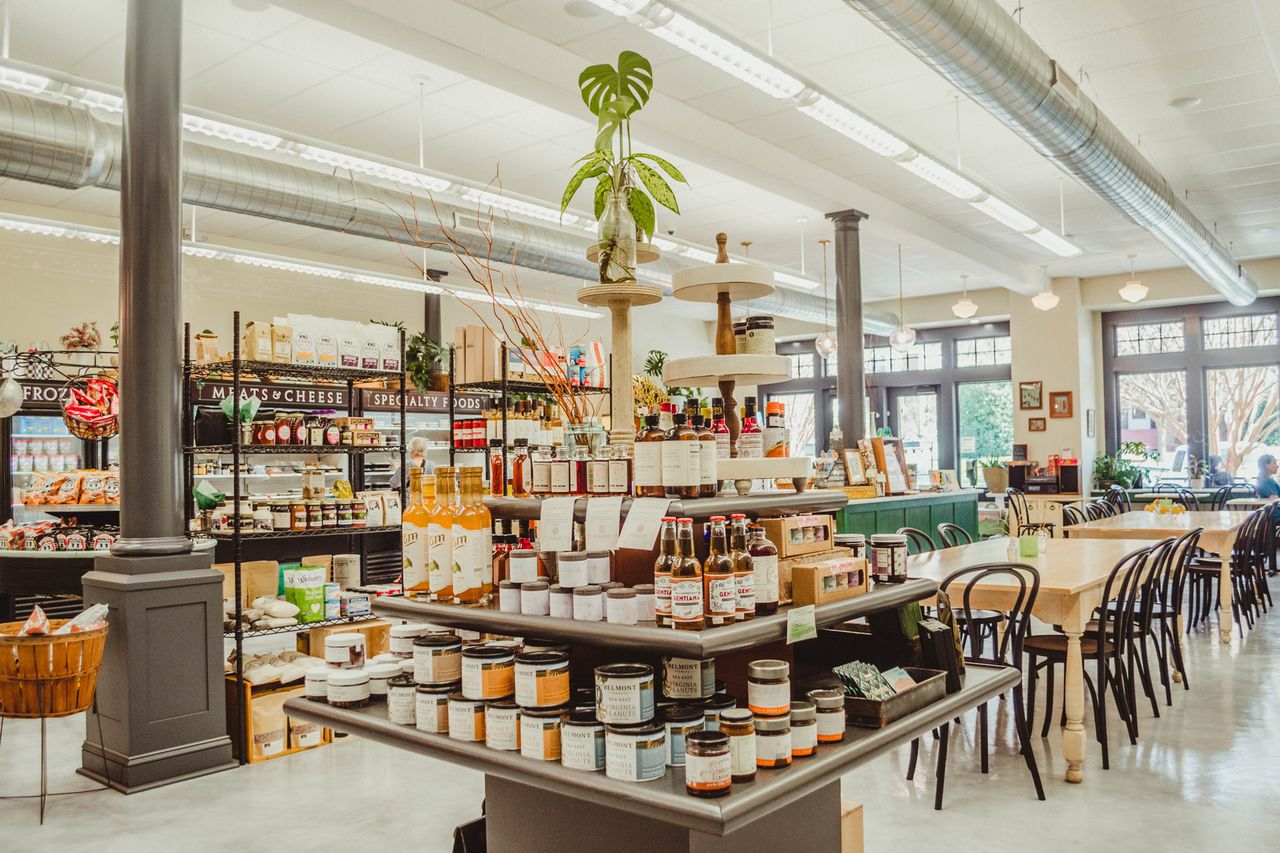 An interior view of a grocery store with shelves products and seating area visible